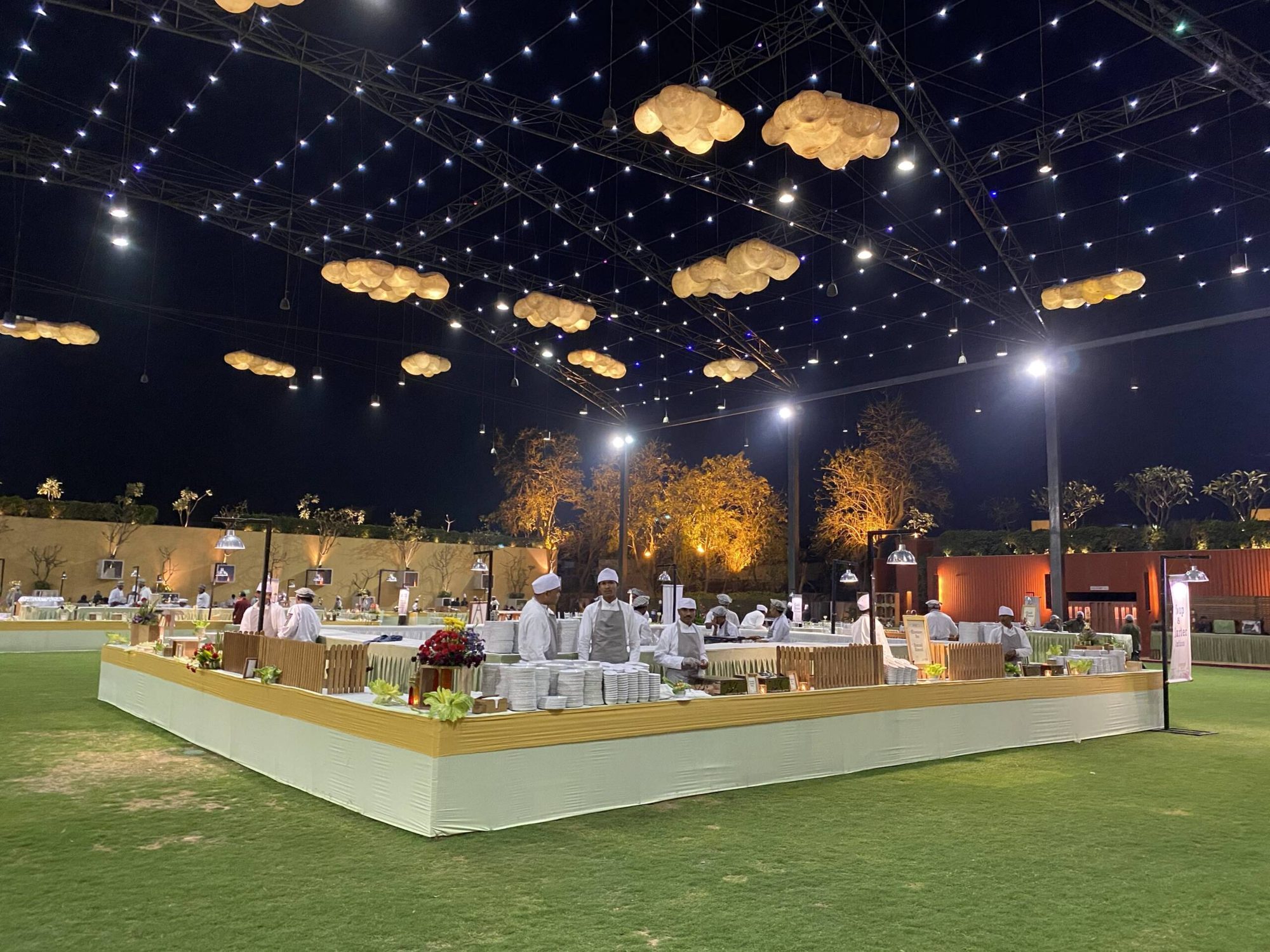 A wedding buffet glowing under a canopy of lanterns, catered by Anushthan